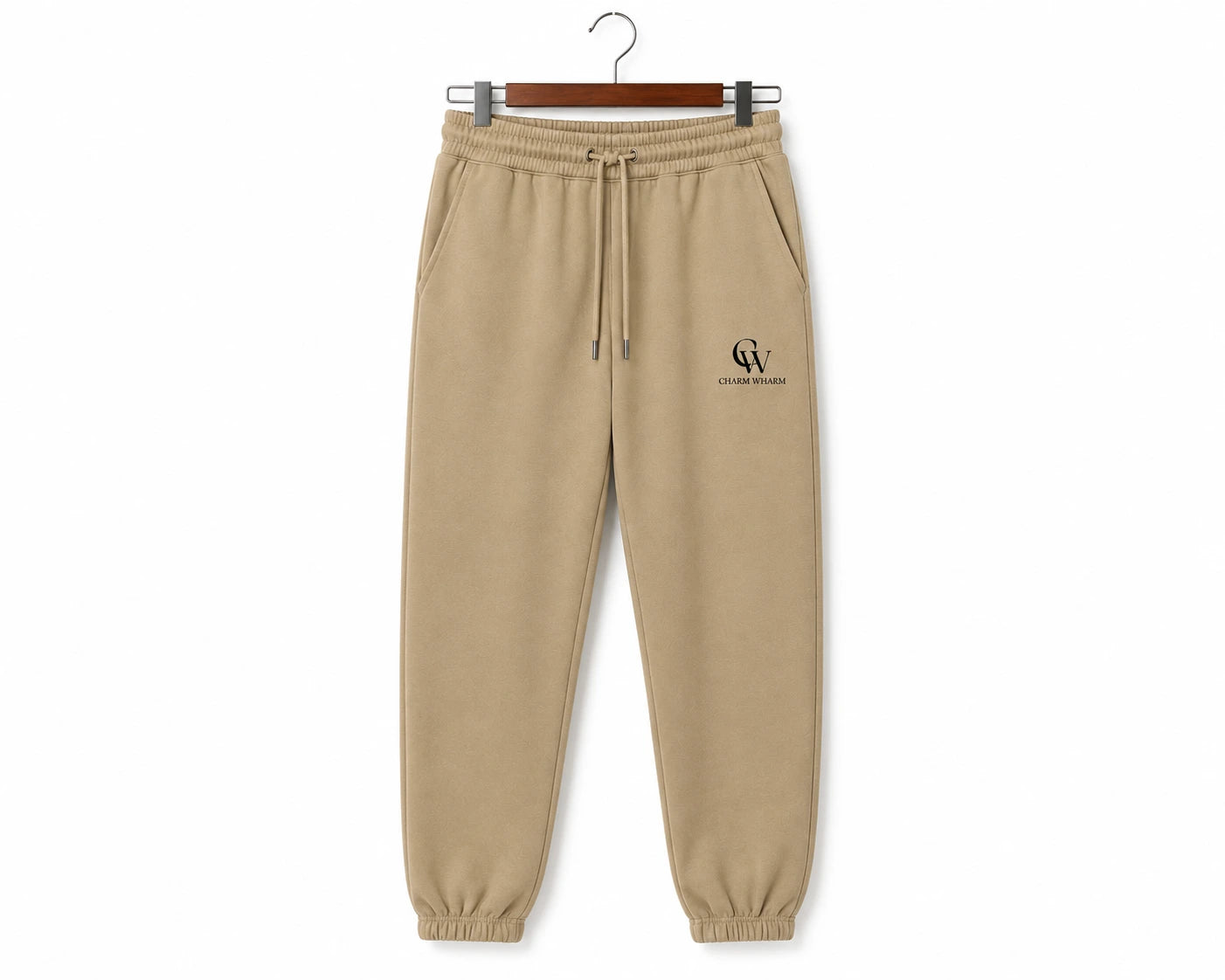 Beige jogger sweatpants with an elastic drawstring waist and elastic cuffs, hanging on a wooden hanger against a white background. A small black 'CW' monogram logo is printed on the left thigh.