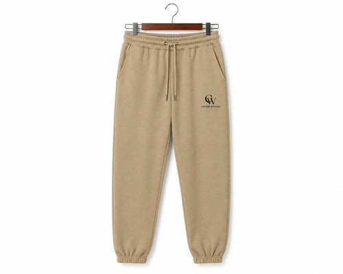 Beige jogger sweatpants with an elastic drawstring waist and elastic cuffs, hanging on a wooden hanger against a white background. A small black 'CW' monogram logo is printed on the left thigh.