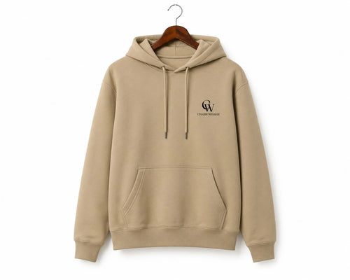 A beige pullover hoodie with a small black embroidered logo on the left chest, hanging on a wooden hanger against a plain white background.